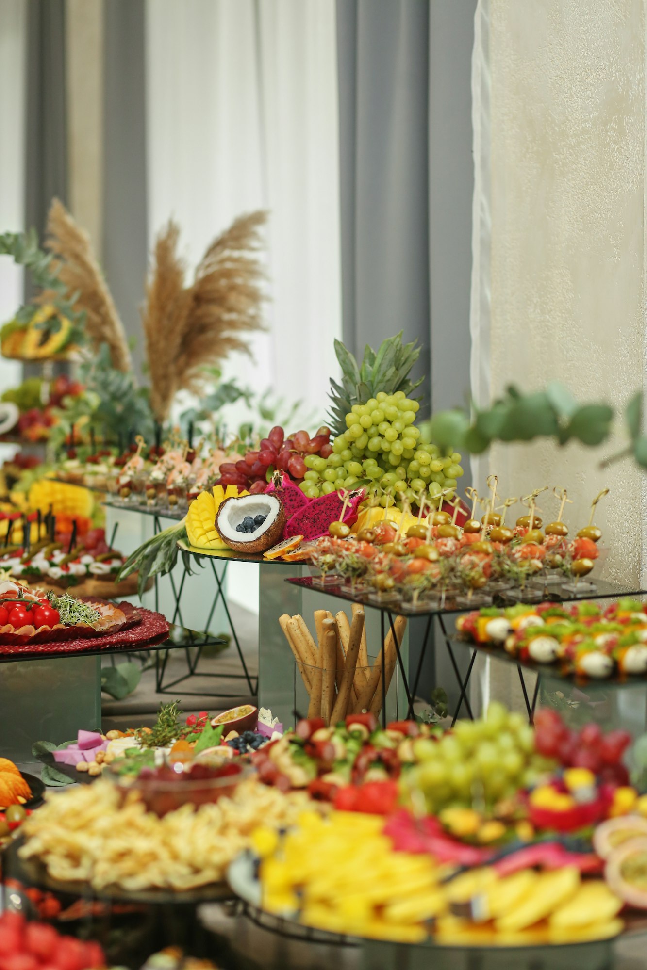 Catering buffet table with snacks and appetizers. Set of varios fruits and berries. Decorative vase